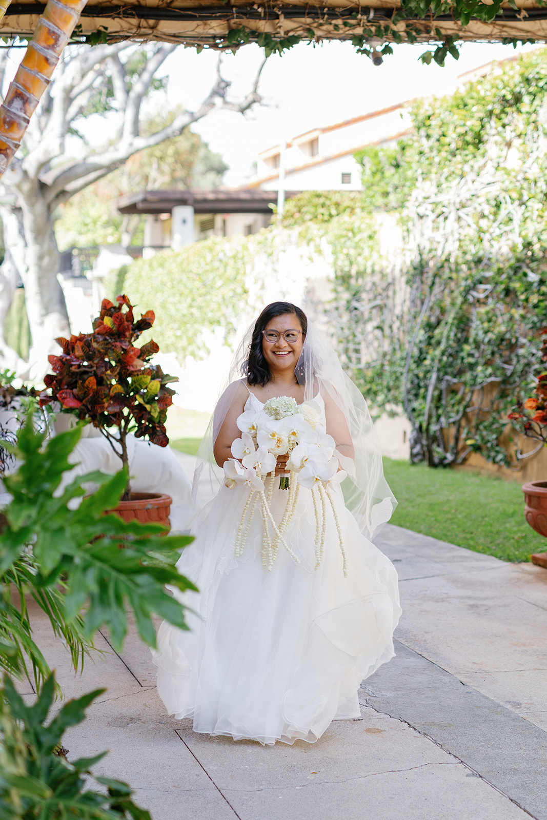 a bride holding a bouquet walking down a sidewalk on the day of her wedding 