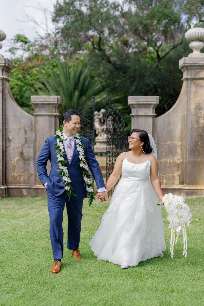 a couple walking hand in hand and smiling taking wedding portraits at la pietra 