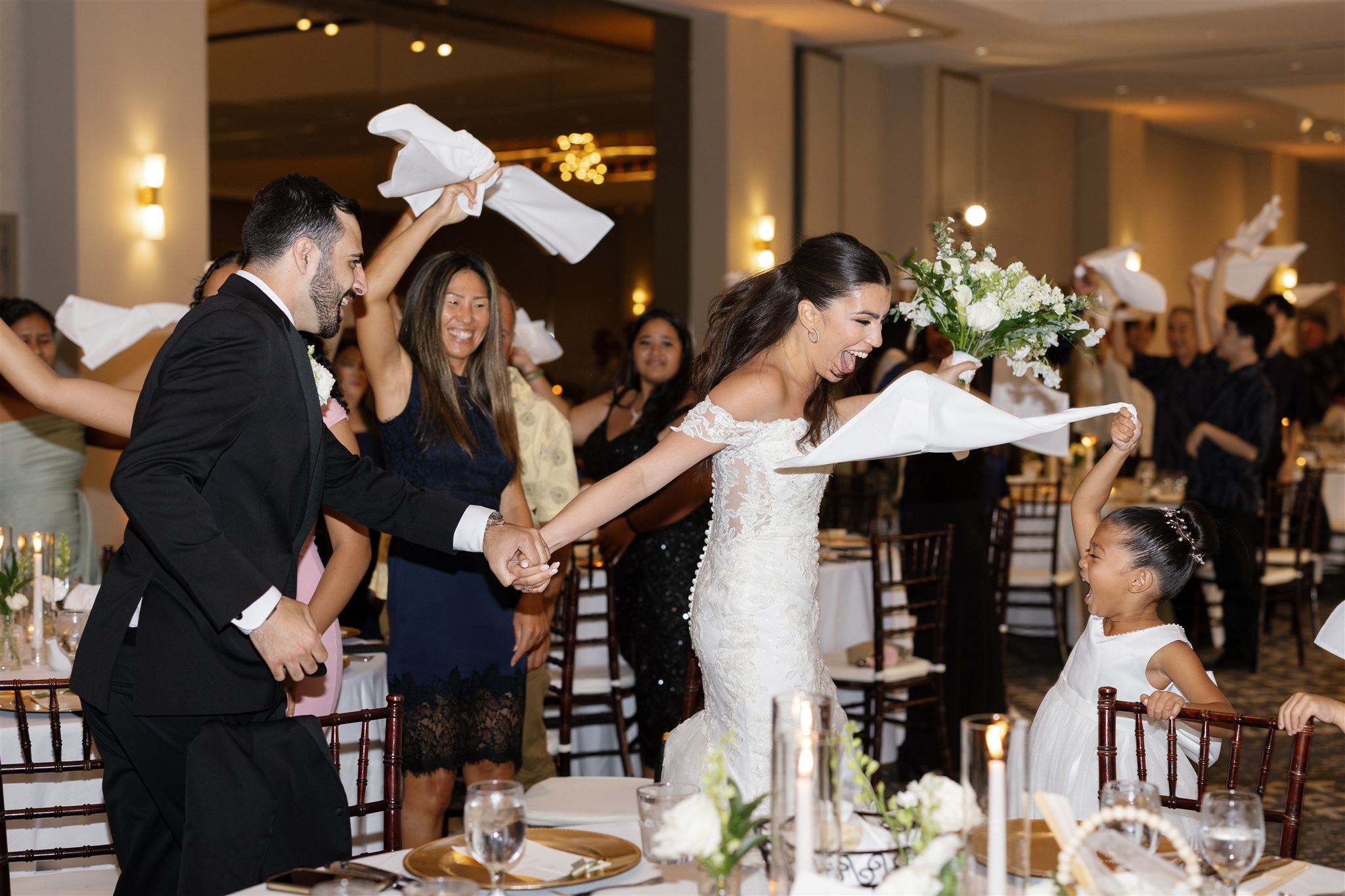 a couple dancing and cheering at their wedding reception at Ritz-Carlton O'ahu, Turtle Bay as their guests cheer and dance with them 