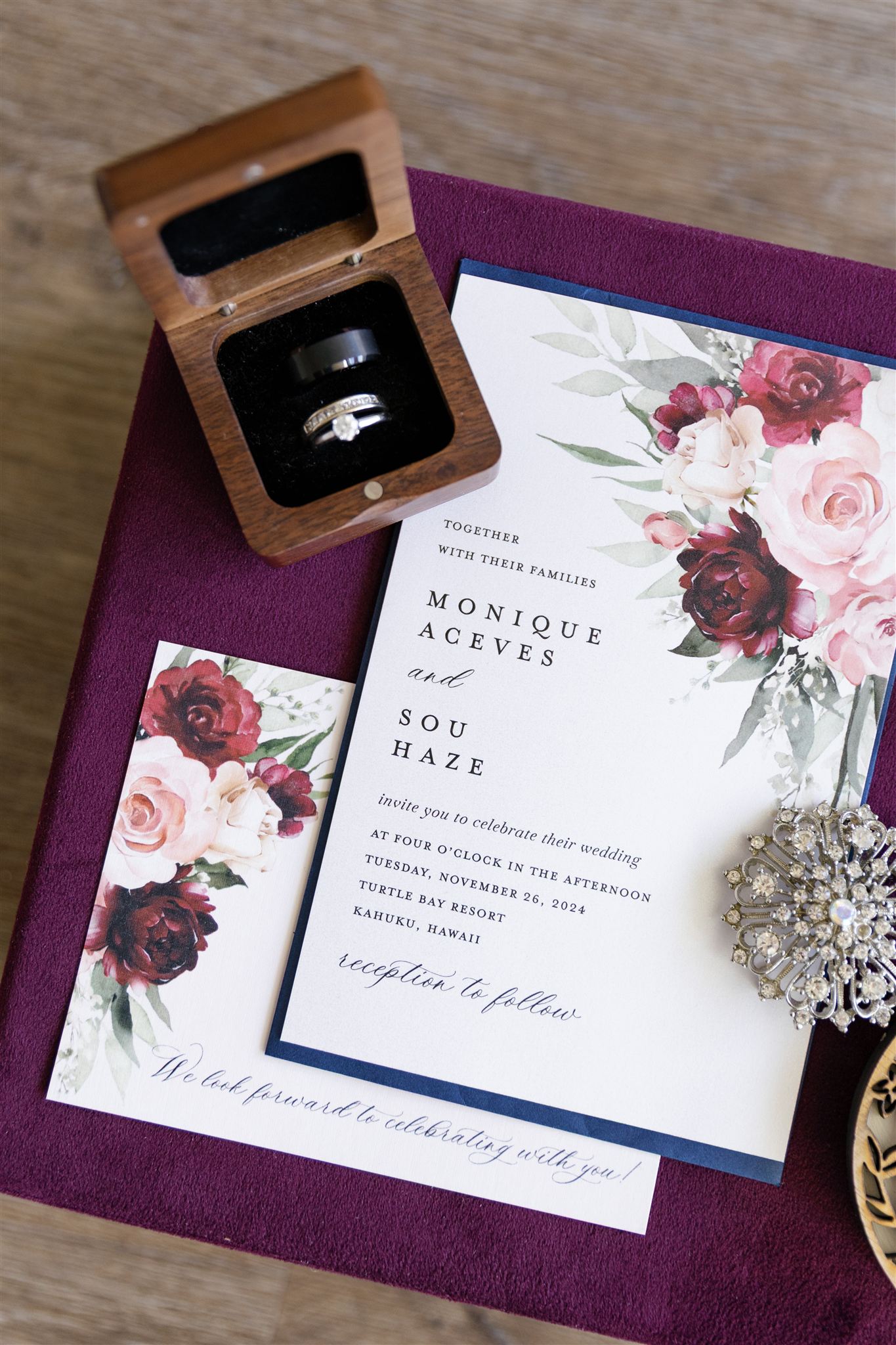 a wedding detail flat lay with wedding invitations, rings  and a brooch 