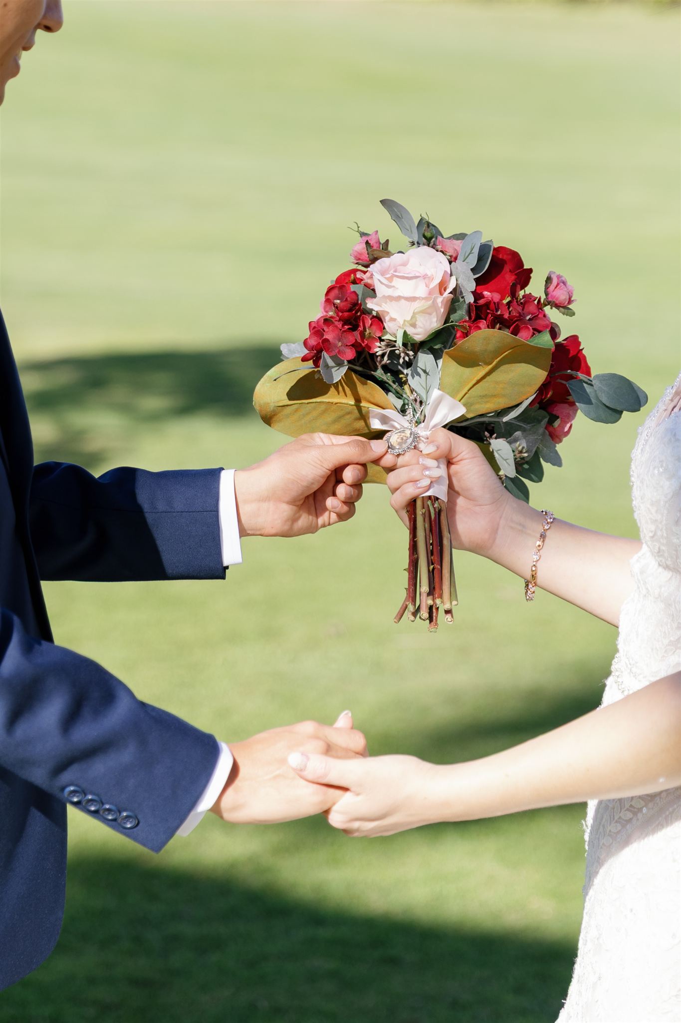 a couple holding hands and the bride is also holding a floral bouquet 
