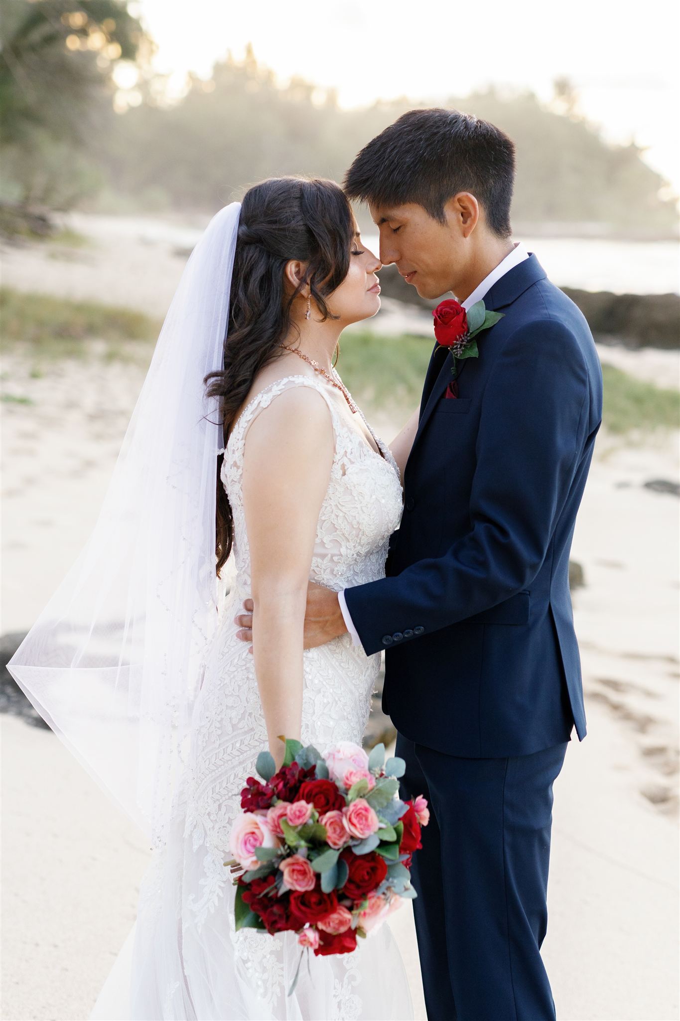 a couple embracing and taking wedding portraits in the sand 