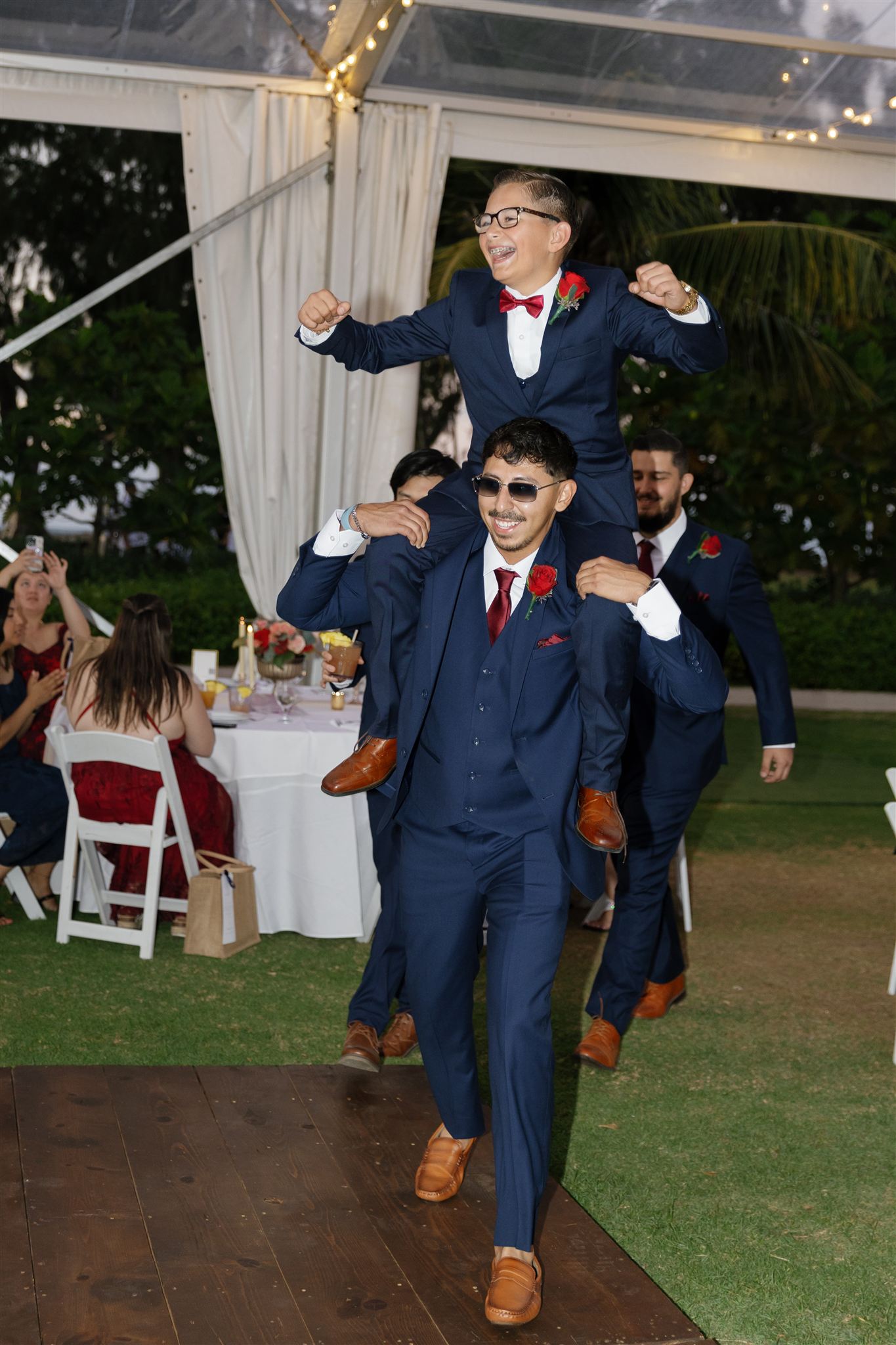 a groomsmen carrying another groomsment on his shoulders entering a wedding reception 