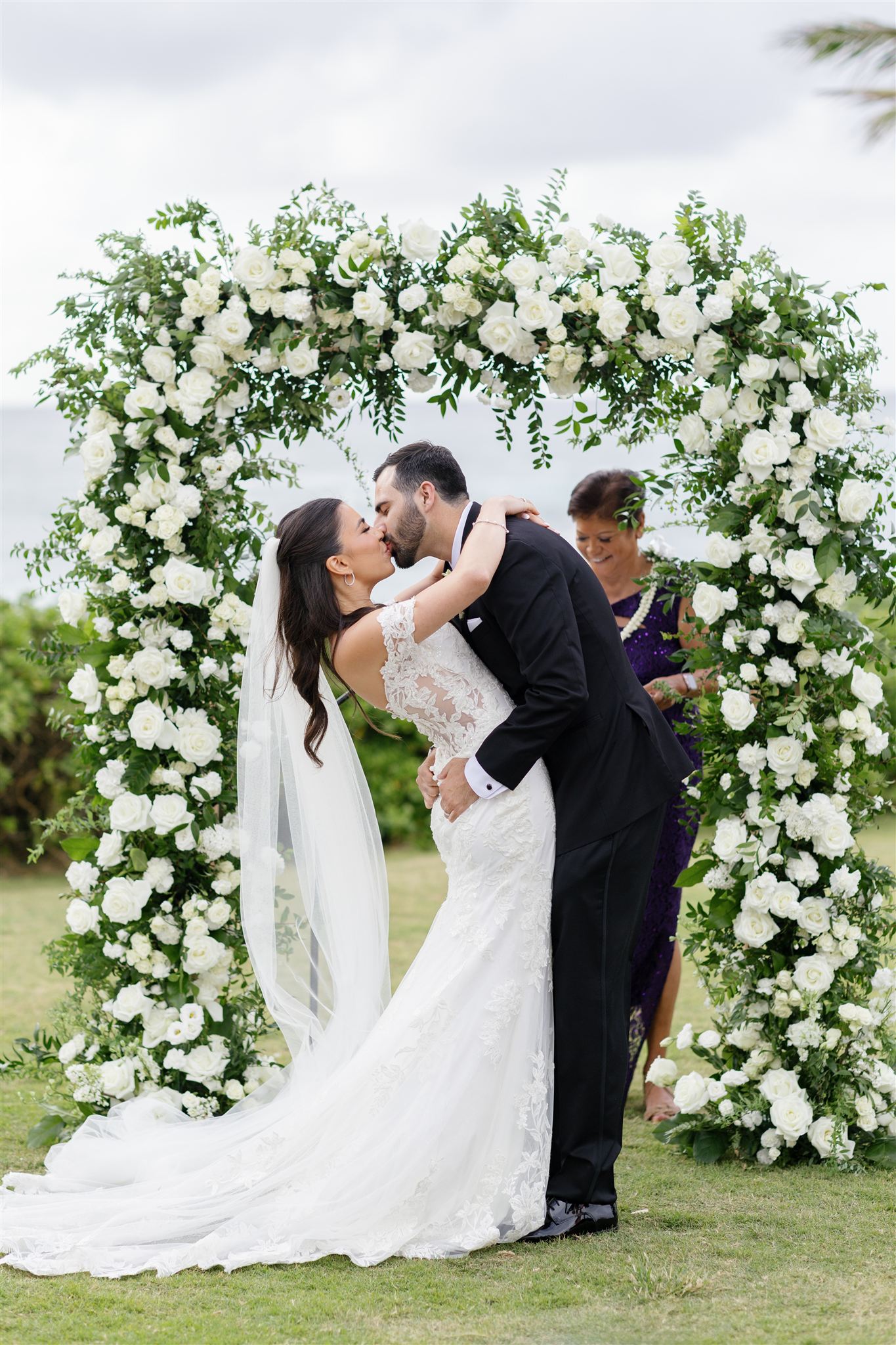 a couple kissing in front of a floral arch during their wedding ceremony at Ritz-Carlton O'ahu, Turtle Bay