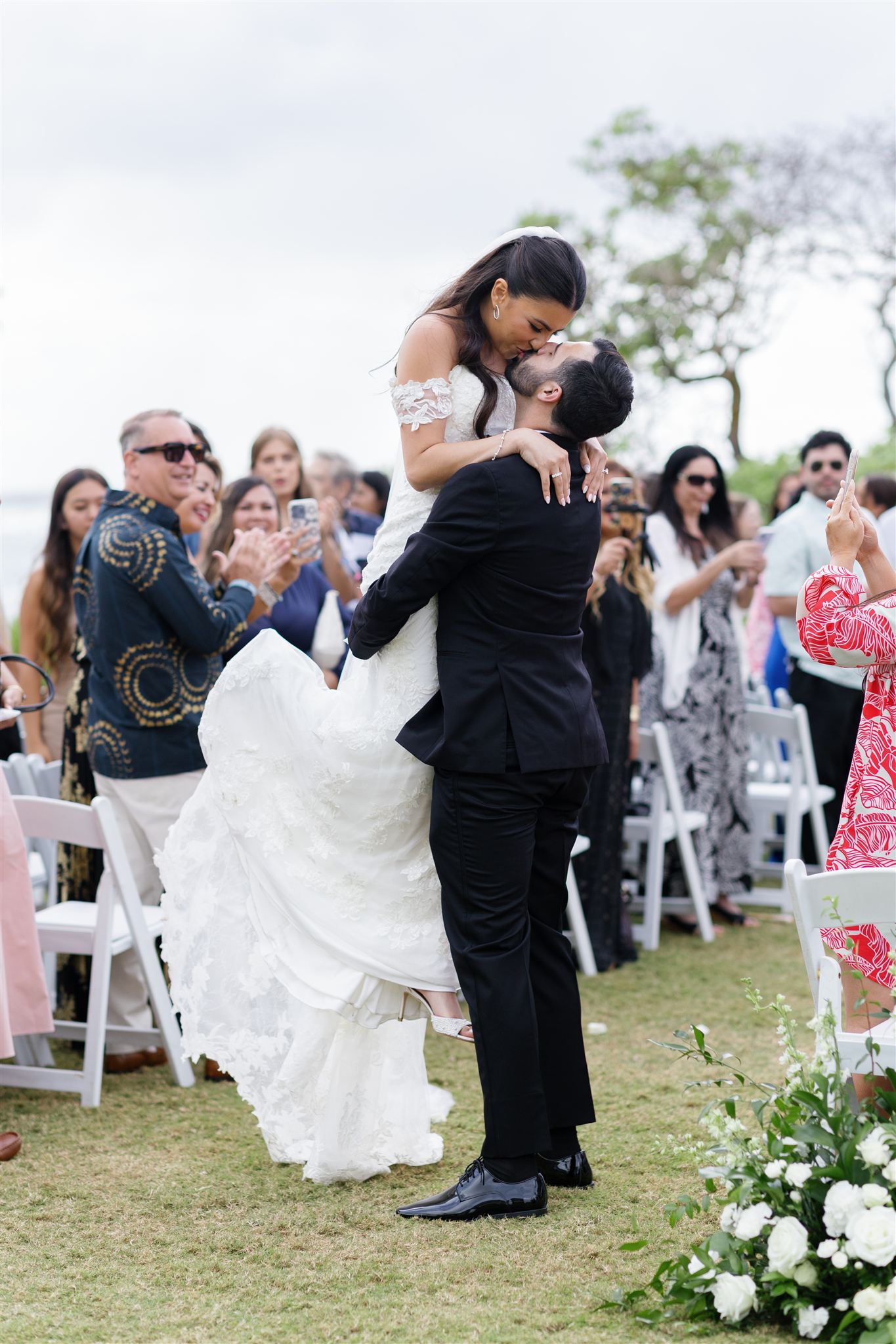 a groom picking up his bride at their wedding ceremony and kissing her 
