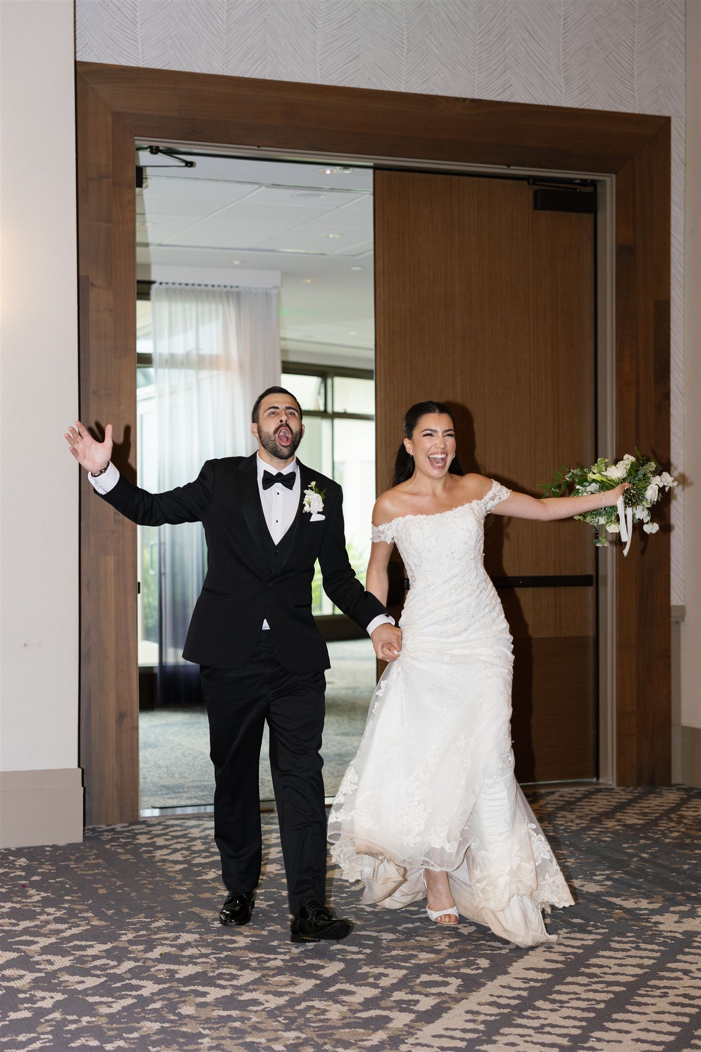 a couple holding hands and entering their wedding reception 