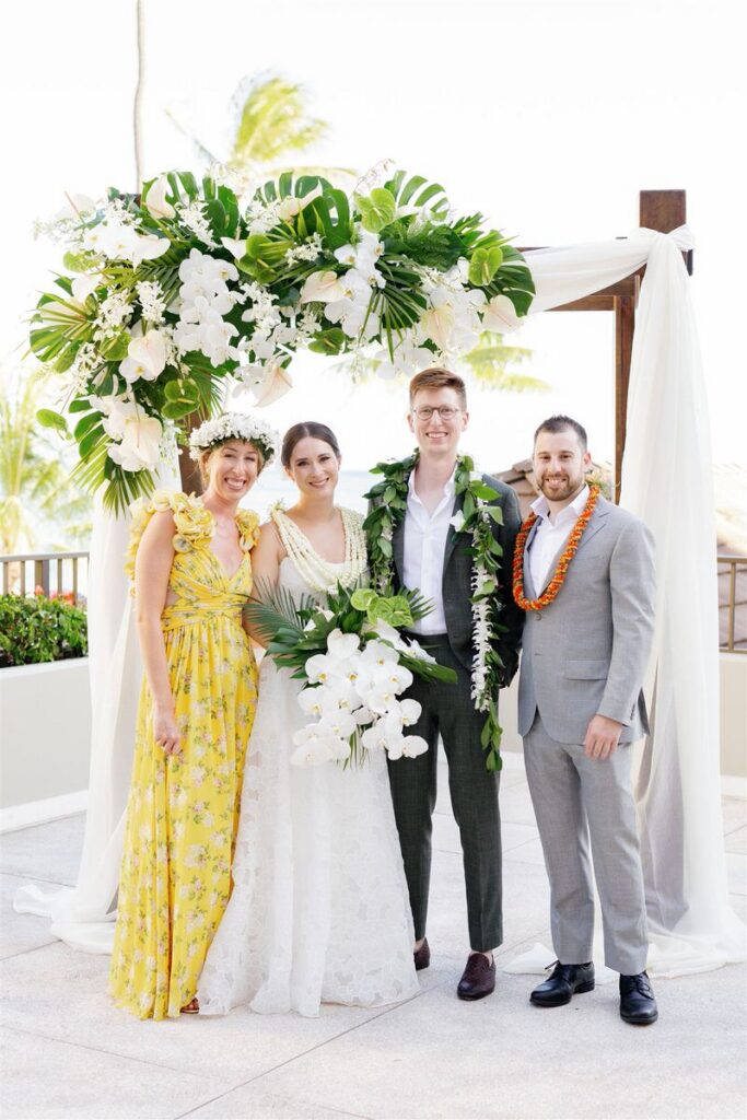 Newlyweds smiling with their wedding party on either side of them 