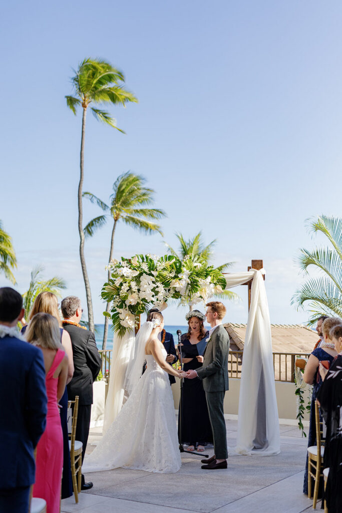 Newlyweds holding hands as their officiant talks during their wedding ceremony 