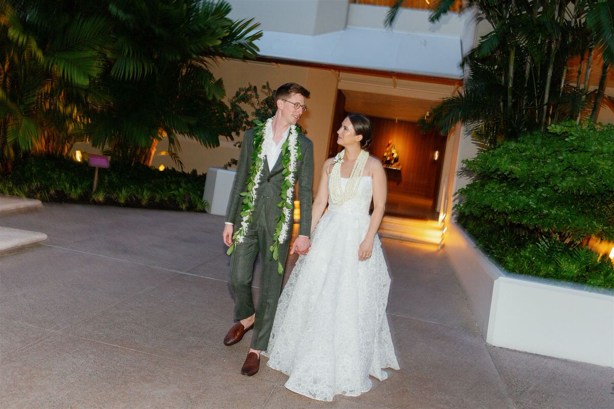 Newlyweds holding hands and walking together after their Halekulani hau terrace wedding