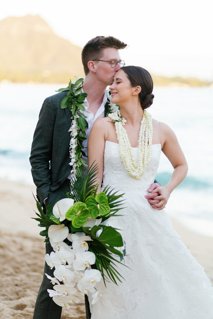 A newlywed standing behind their partner and kissing their head 