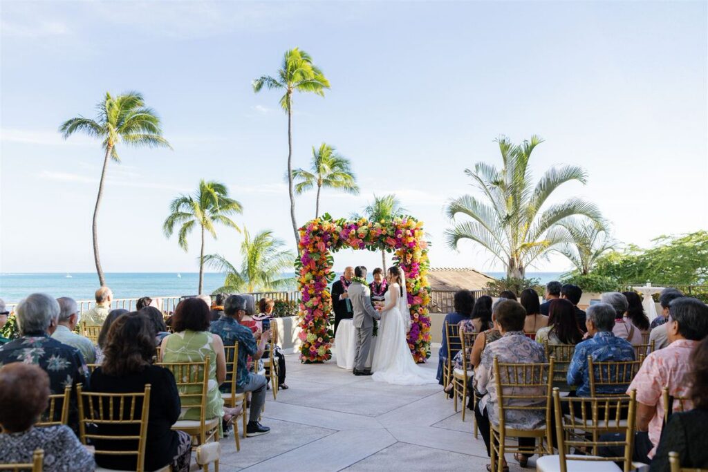 Newlyweds holding has as they stand up during their wedding ceremony 