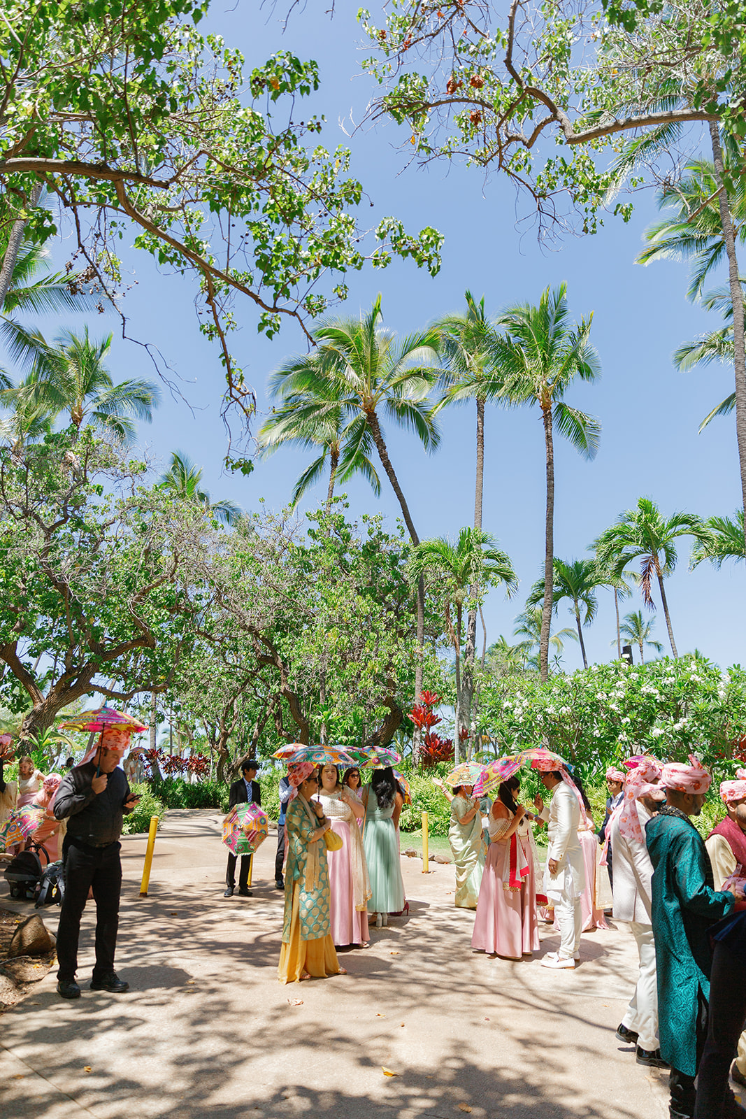 wedding guests holding colorful umbrellas waiting for a wedding ceremony to begin at  the Four Seasons Resort on Oahu