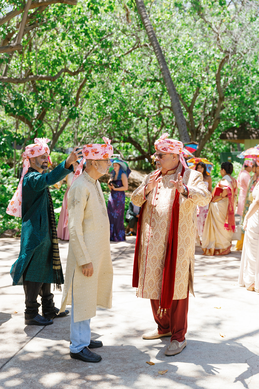 a group of men talking to each toher wearing pink turbans