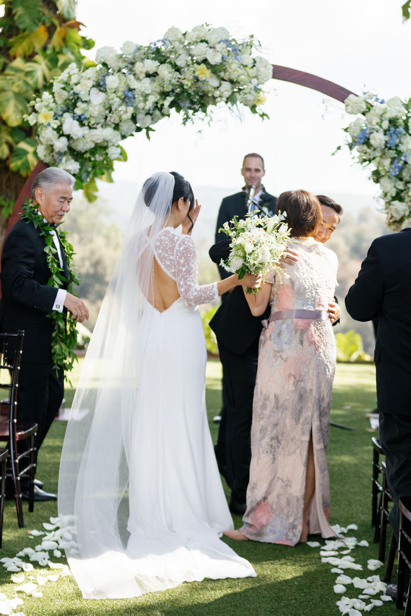 a bride and groom hugging their family members before their outdoor wedding ceremony