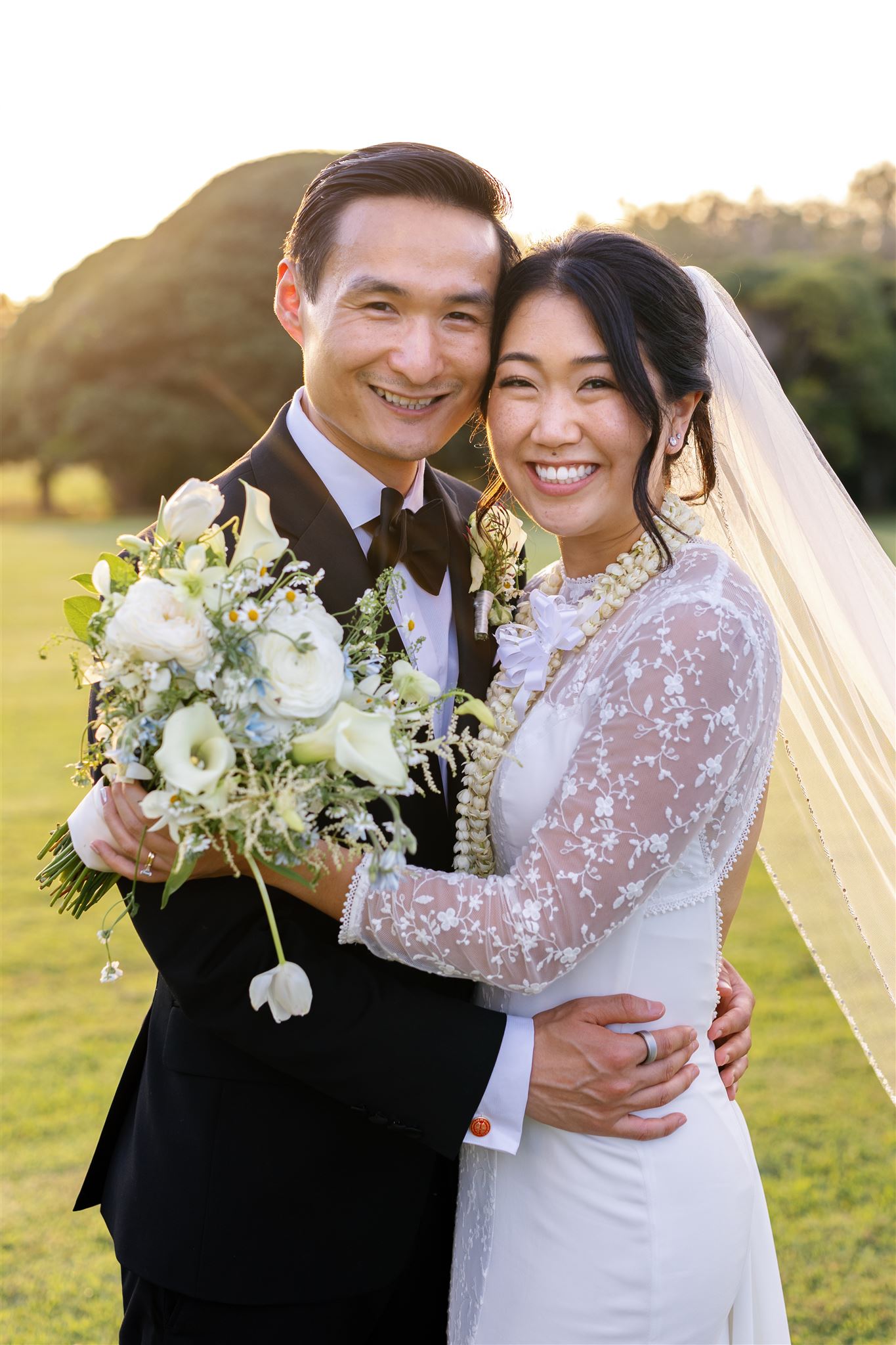 a couple taking wedding portraits at sunset on the lawn of sunset ranch in hawaii 