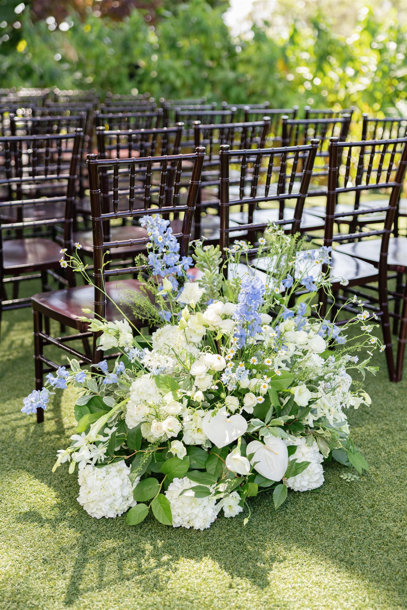 a white and blue floral arrangement for a wedding next to chairs 
