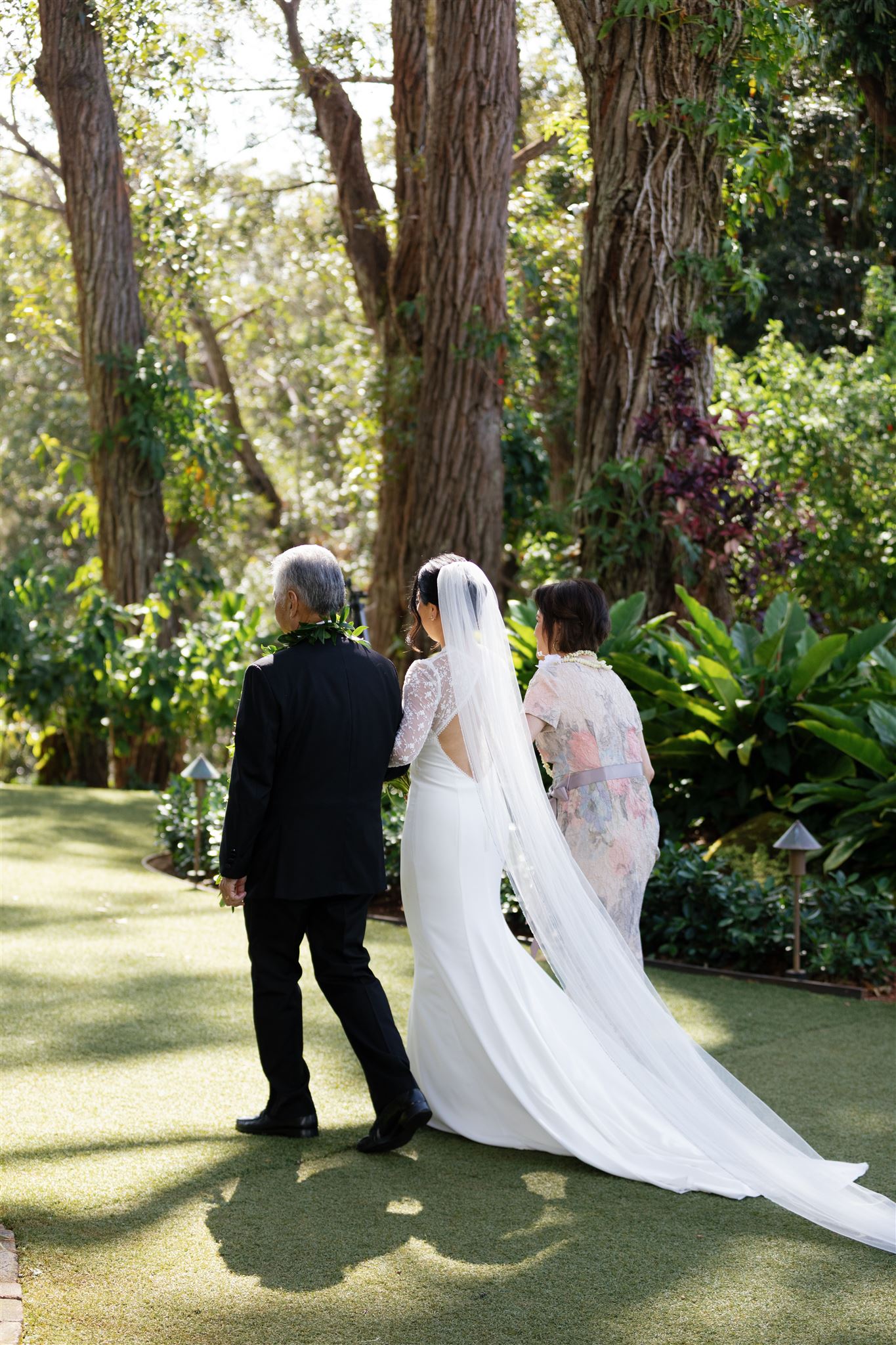 a bride walking arm in arm with her mother and father down the aisle