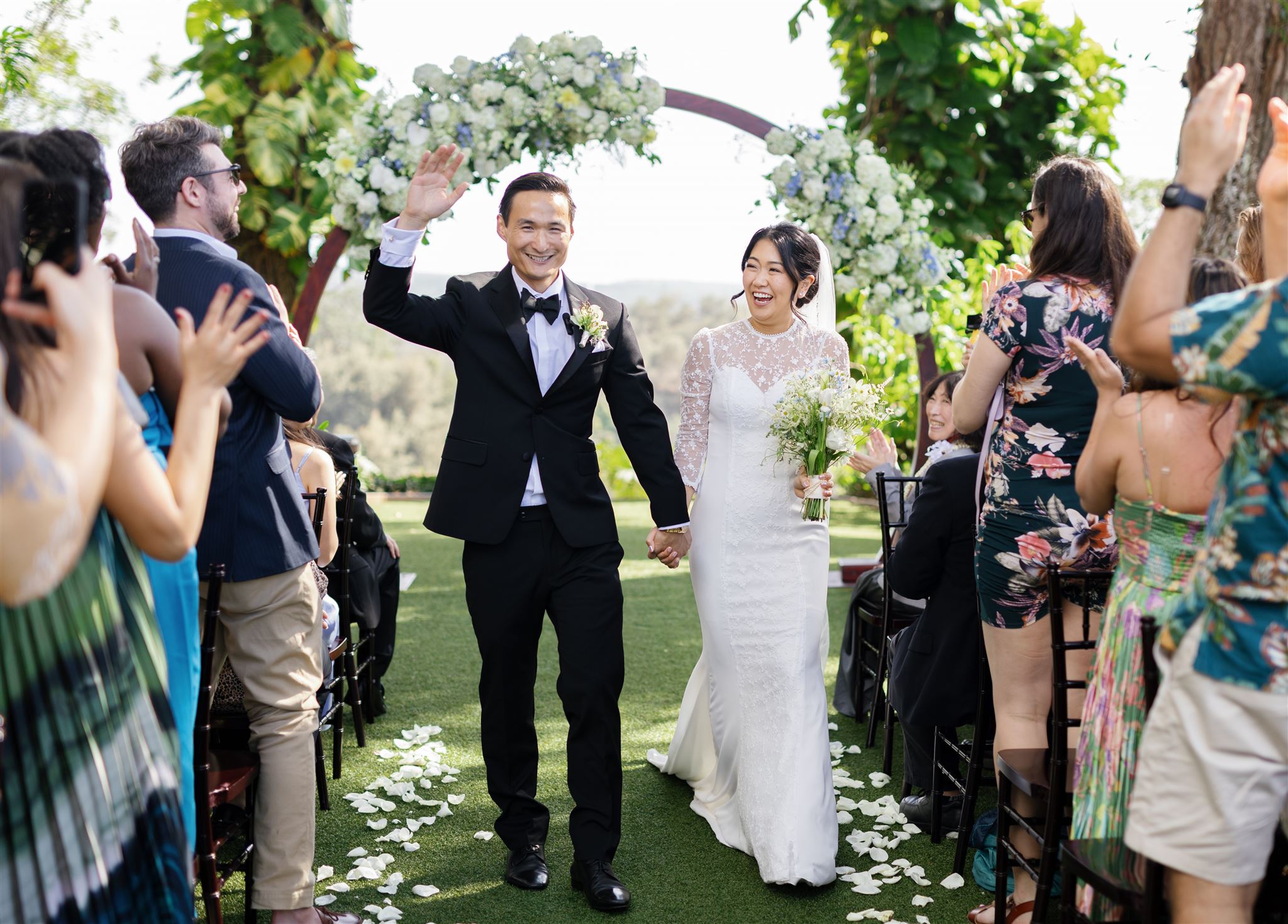 a husband and wife smiling and walking down the aisle to their guests cheering after their wedding ceremony at sunset ranch in hawaii 