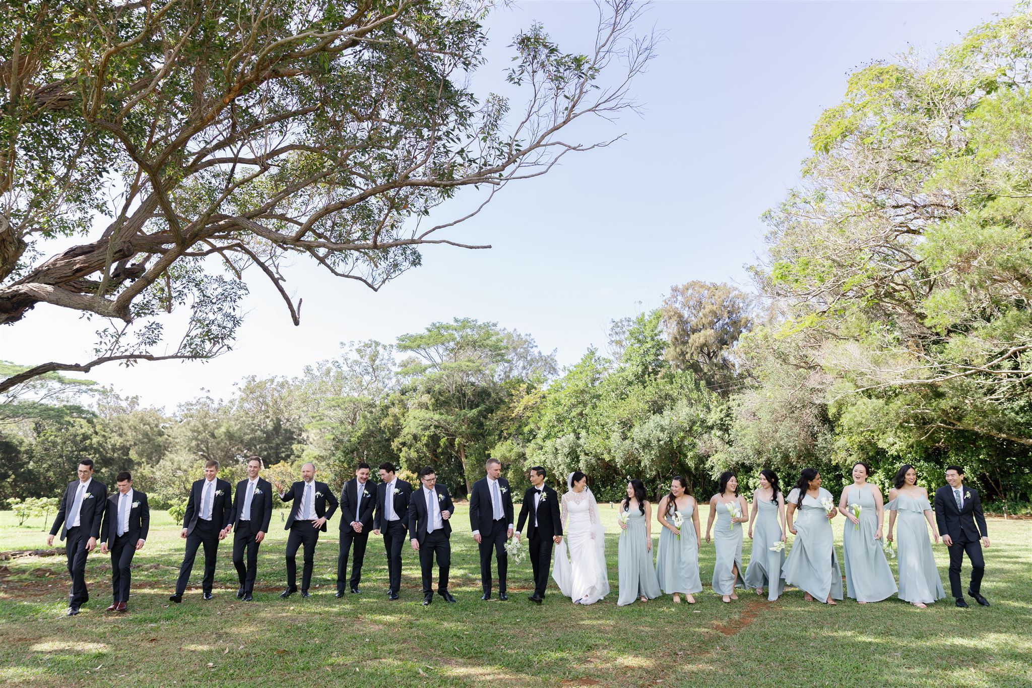a bride and groom with their wedding party taking a group portrait