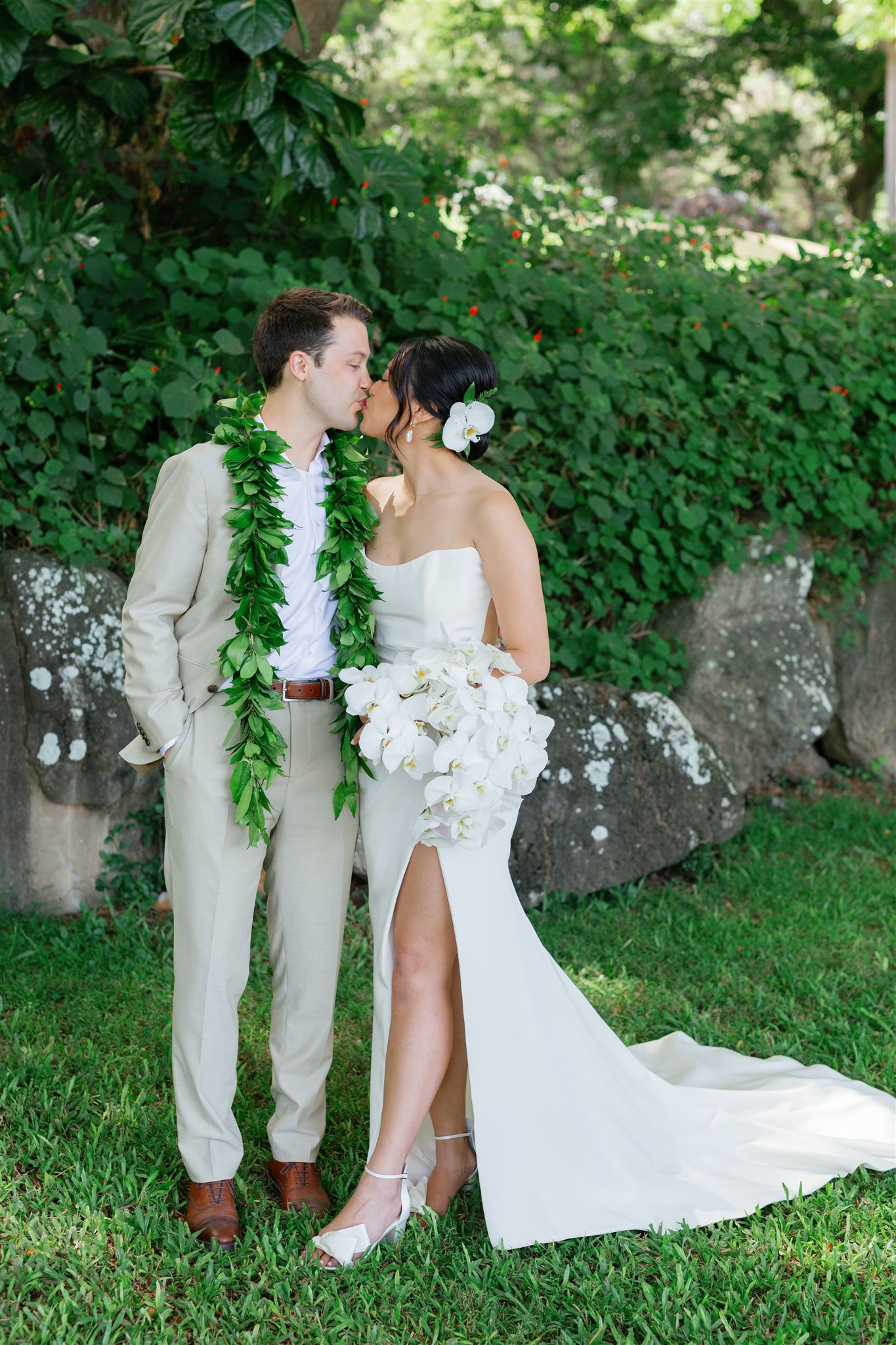a bride and groom kissing the bride is holding a bouquet made up of white orchids 