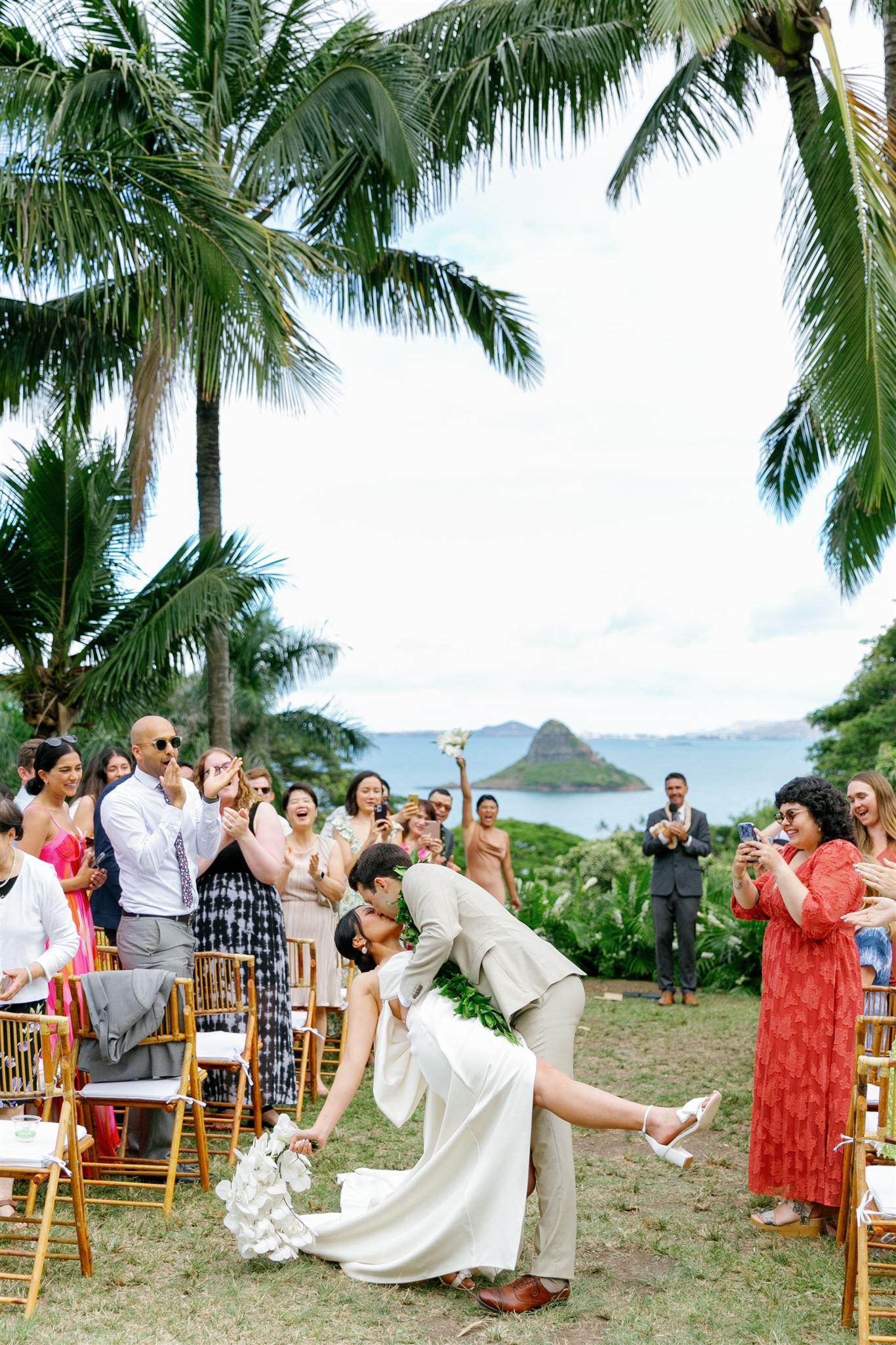 a groom dipping his bride backwards and kissing her after their wedding ceremony at Paliku Gardens at Kualoa Ranch