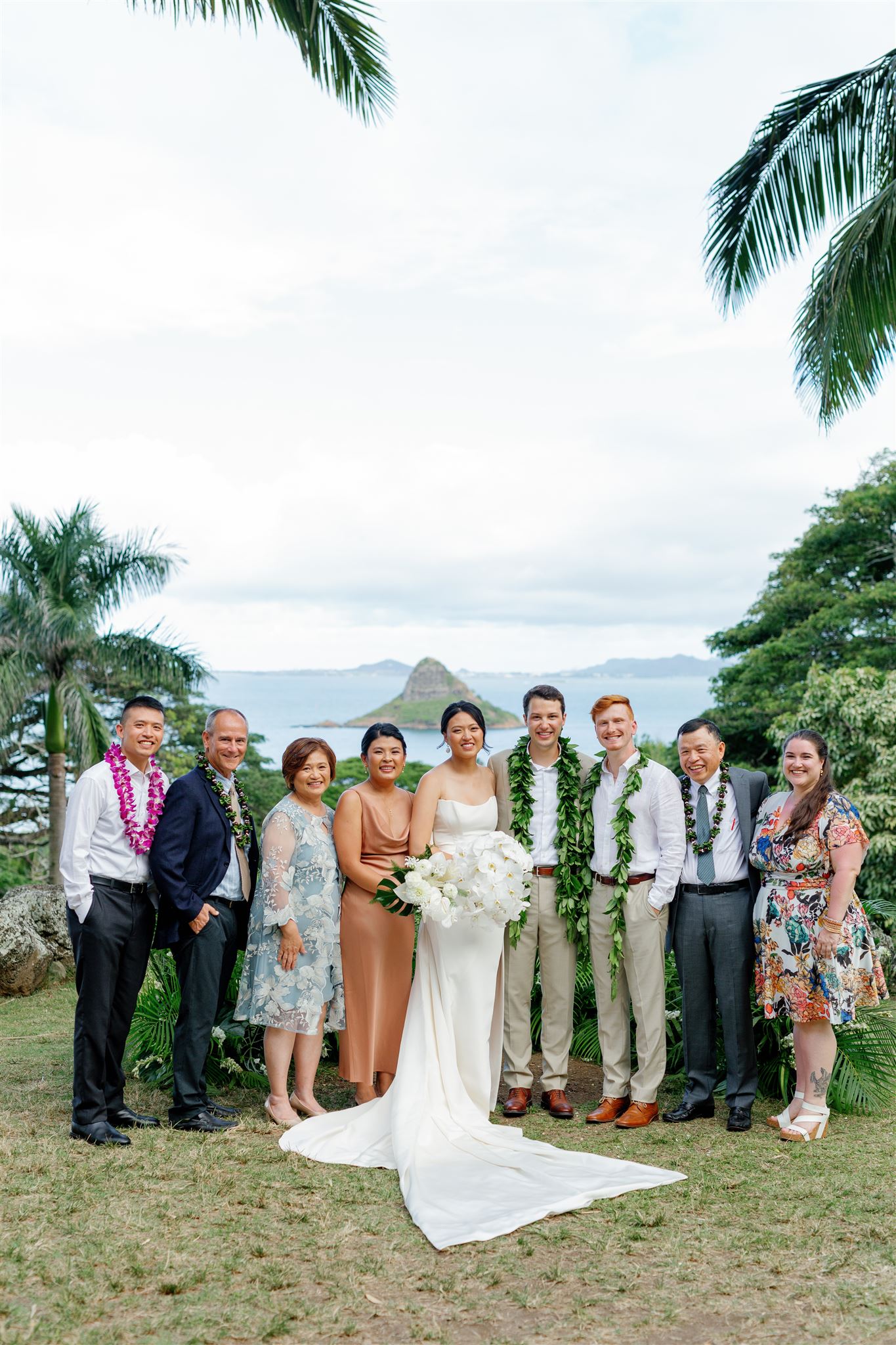 a bride and groom taking a photo with their wedding party and family at Paliku Gardens at Kualoa Ranch