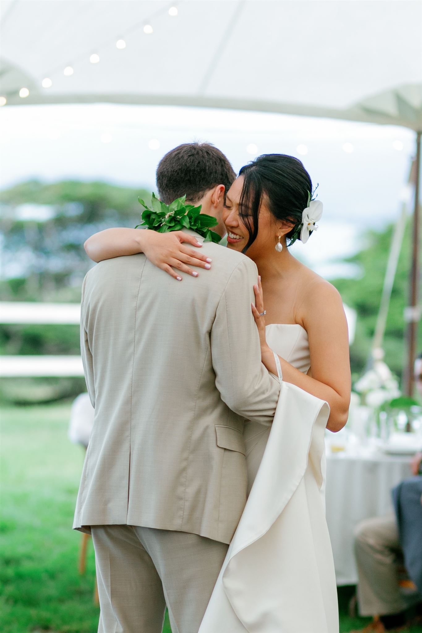 a bride and groom sharing a first dance under a white tent 