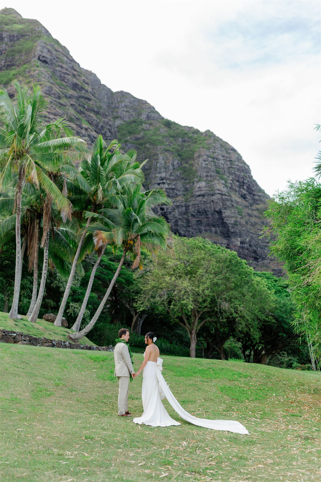 a bride and groom holding hands and taking wedding portraits at Paliku Gardens at Kualoa Ranch