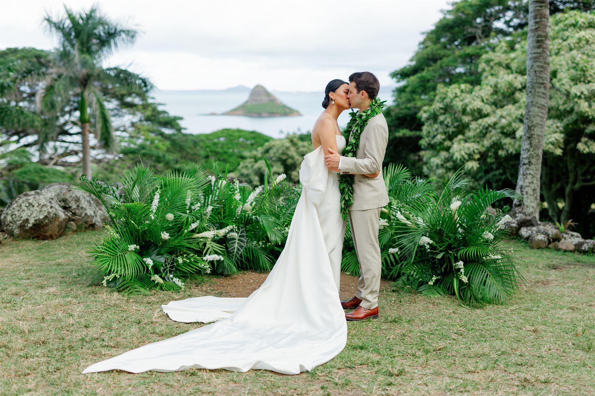 a bride and groom kissing each other at Paliku Gardens at Kualoa Ranch