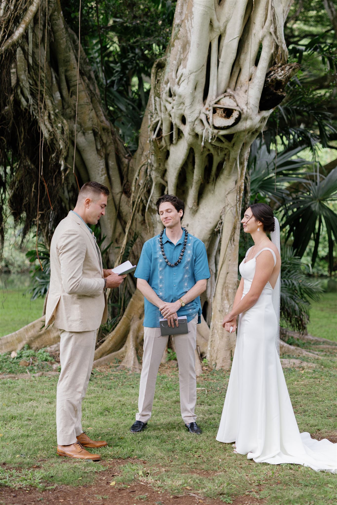 a bride and groom reading vows together at their wedding ceremony at palm meadow in waimea valley