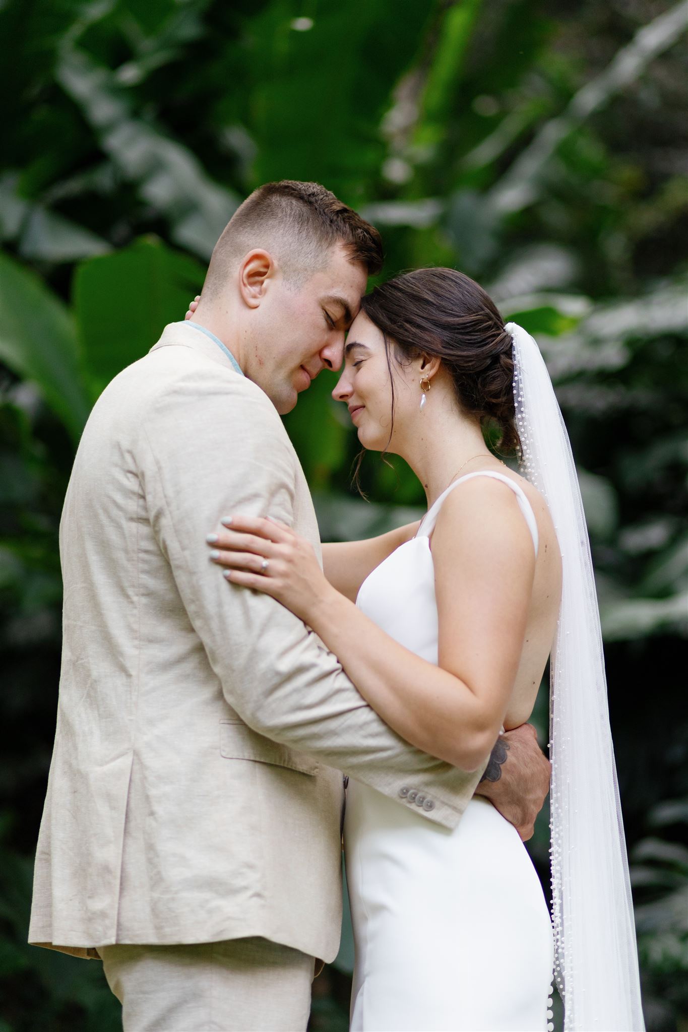 a bride and groom embracing with their heads pressed together