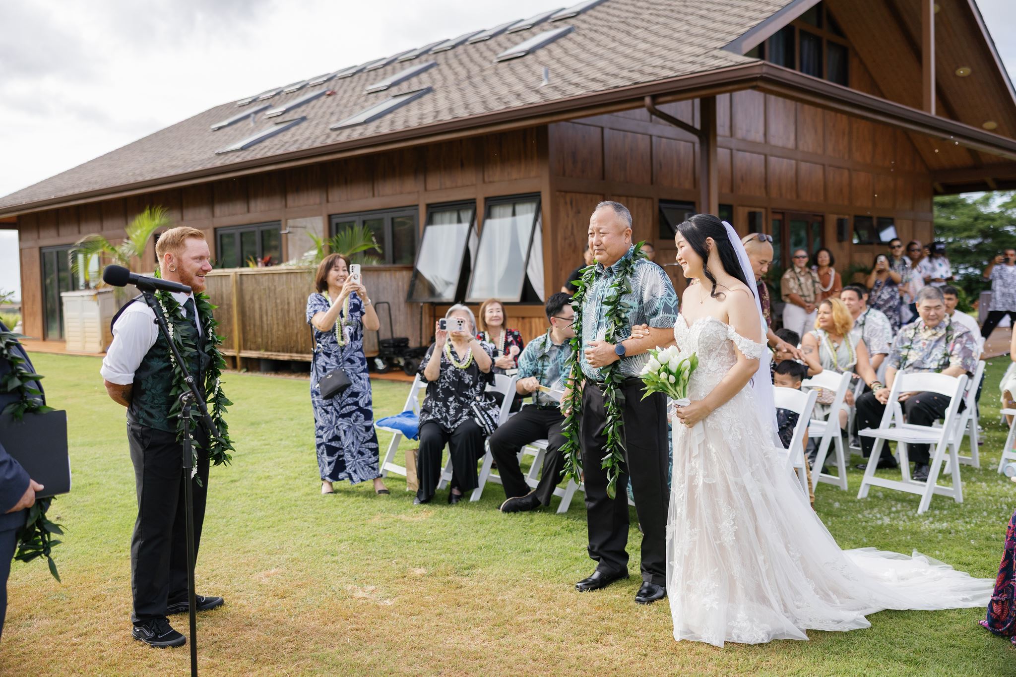 a bride walking down the aisle arm in arm with her father to the groom who is smiling