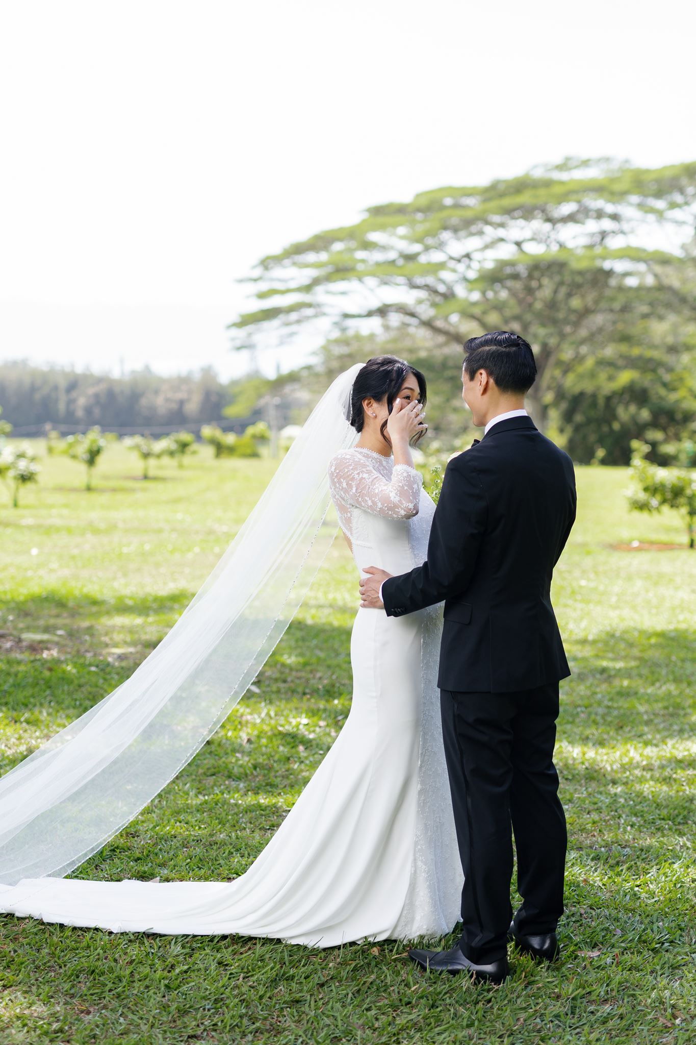 a bride getting emotional and wiping tears from her eyes after sharing a first look with her groom