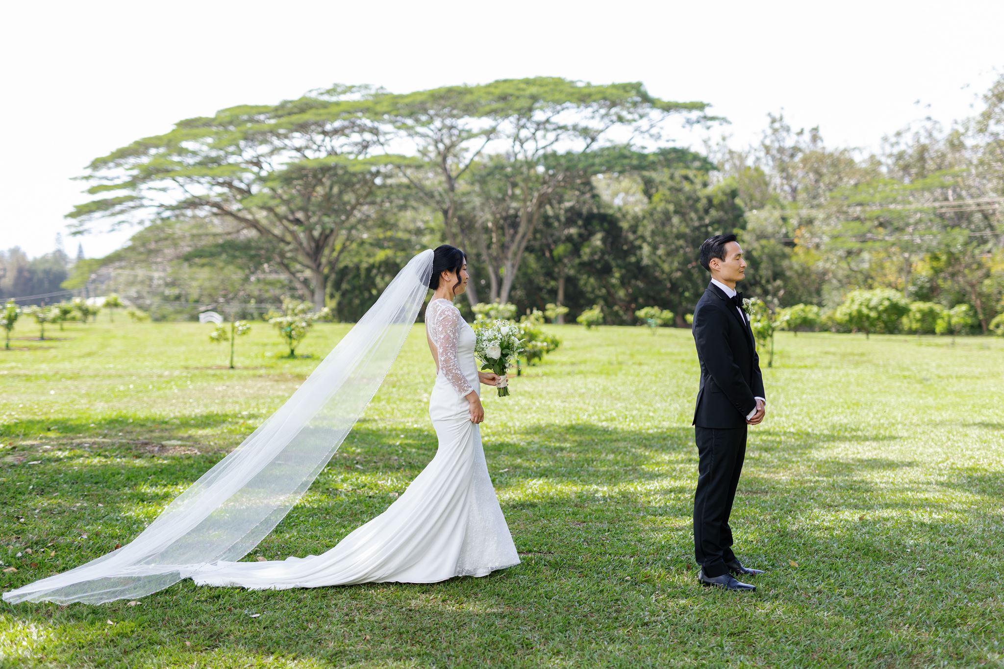a bride walking towards her fiance to through a field her to share a first look her fiance is facing away from her