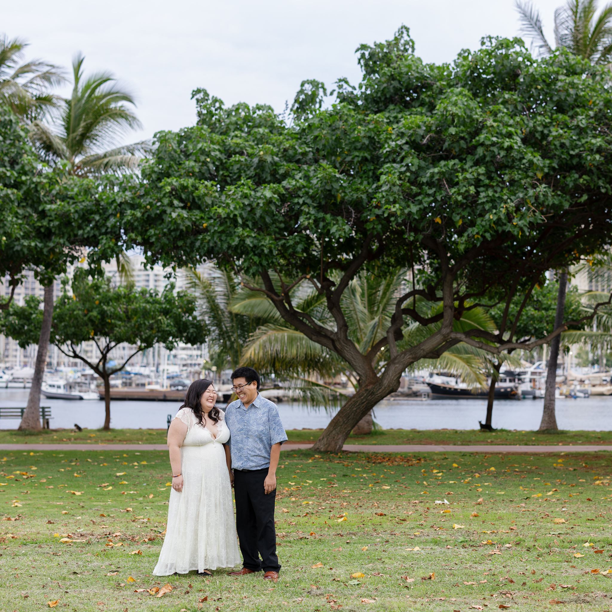 a couple on a grass lawn laughing together during their engagement session