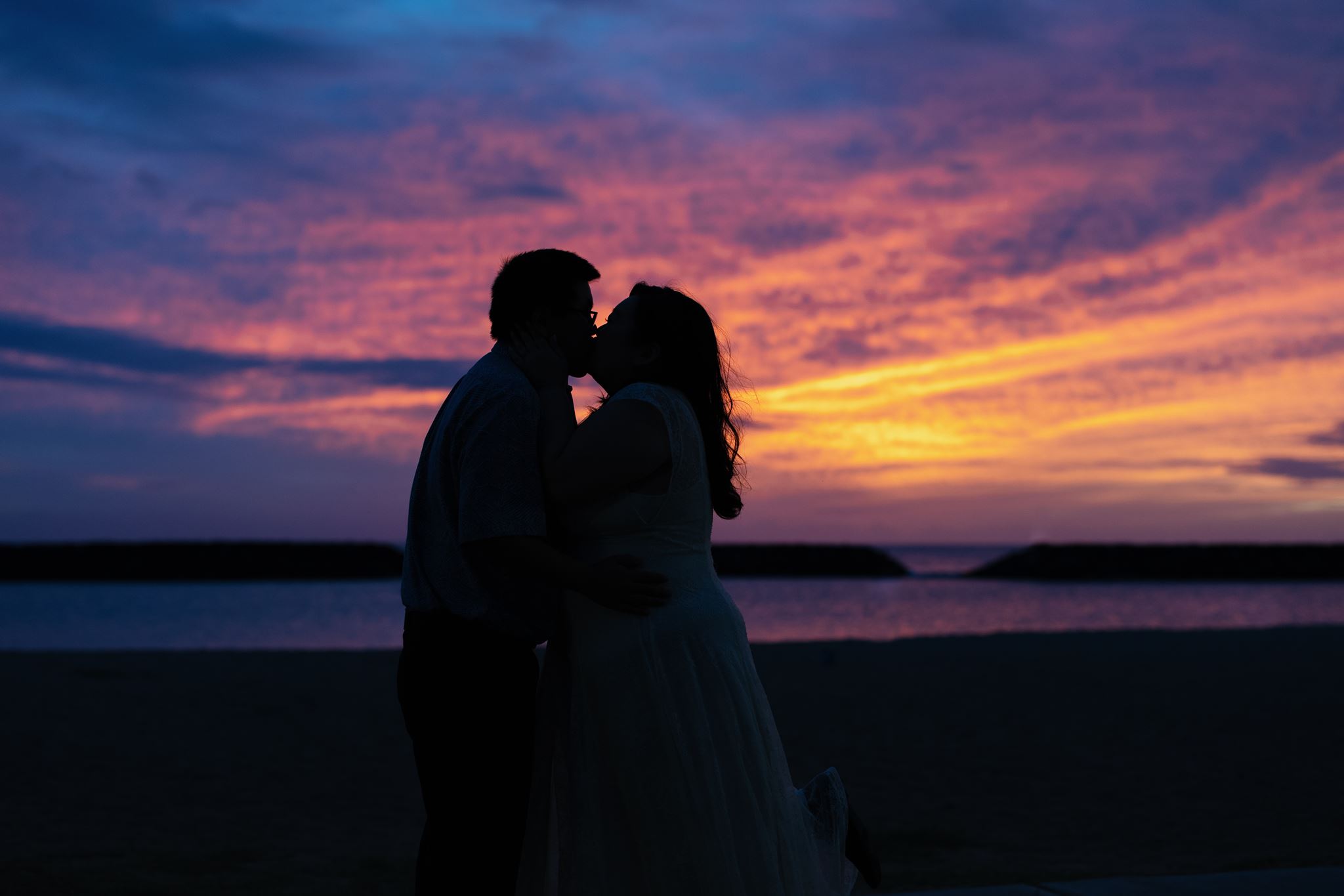 a man and woman kissing at sunset on magic island for their enagement session