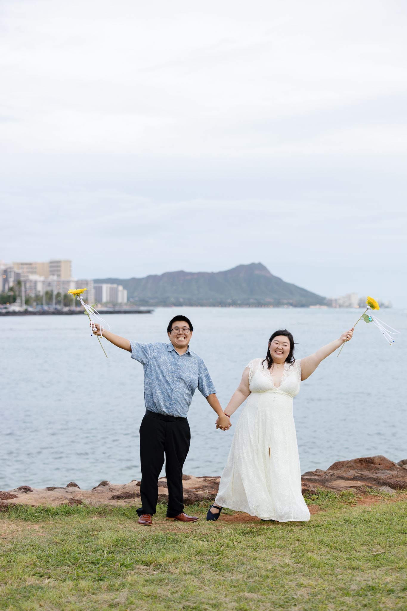 a man and woman laughing and holding hands on magic island they are also both holding up sunflowers