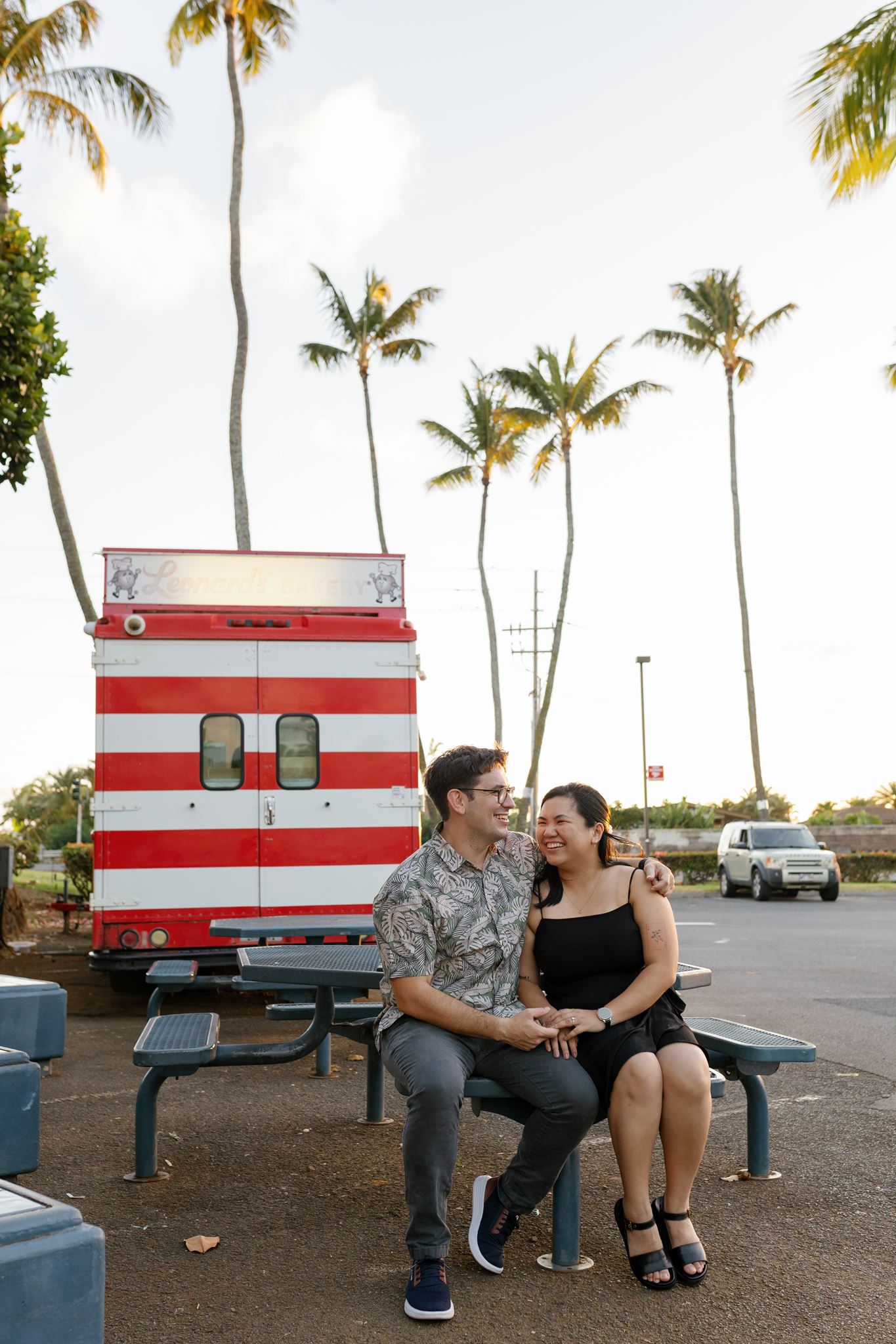 a man and woman sitting on a picnic bench holding hands and laughing