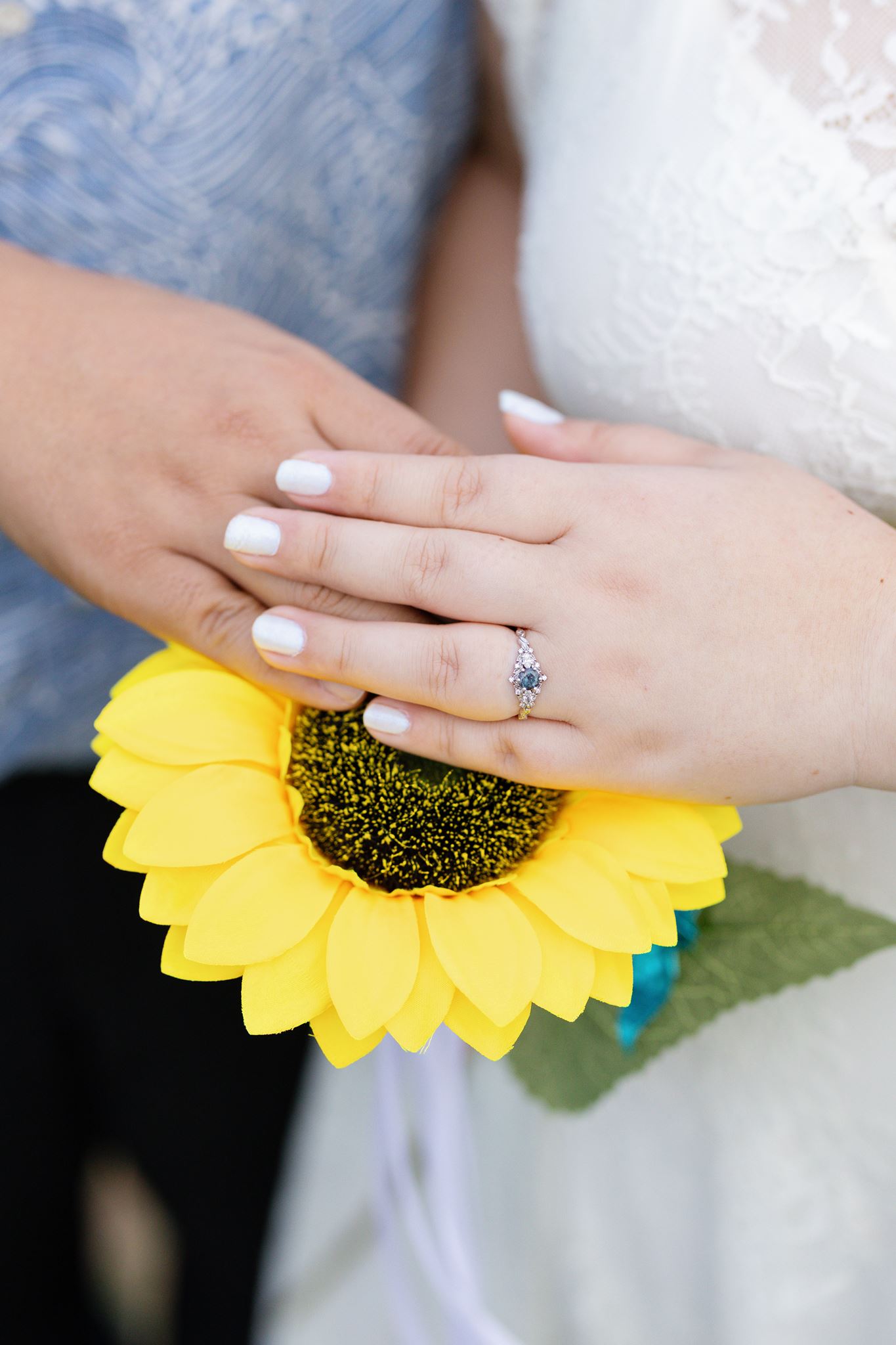 a man and woman holding their hand over a yellow sunflower