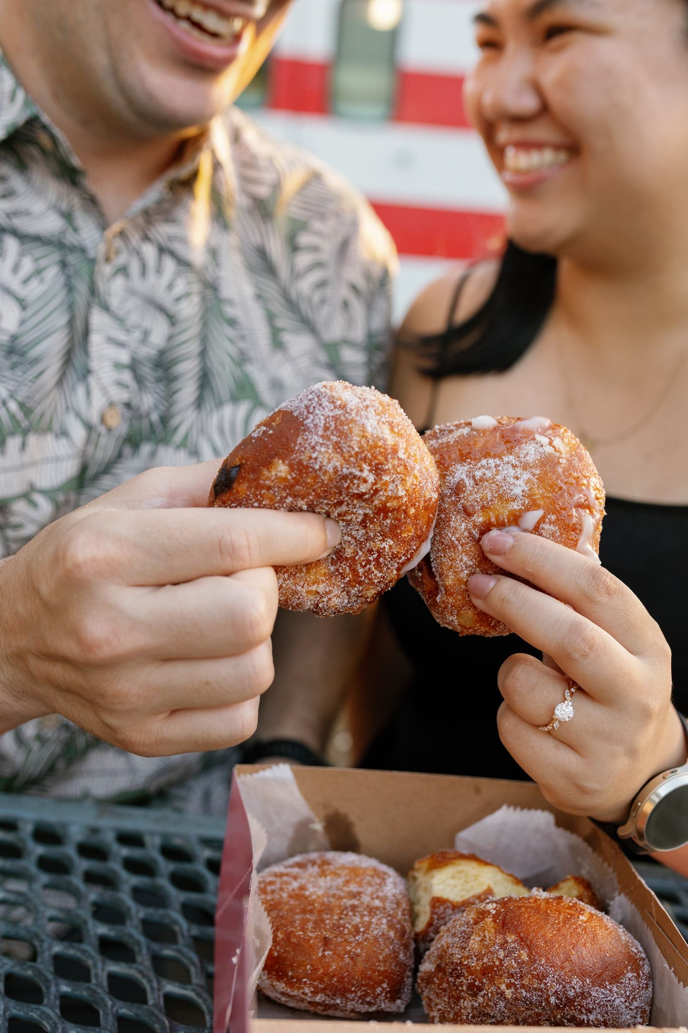 a man and woman sharing donuts together on a picnic bench