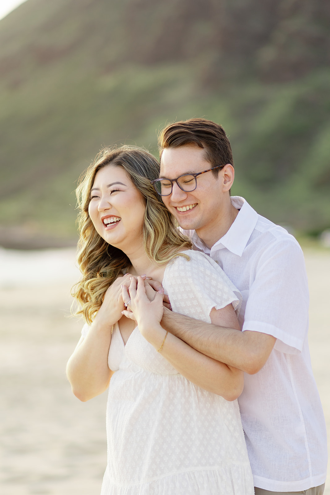 a couple laughing and taking engagement photos at sunset