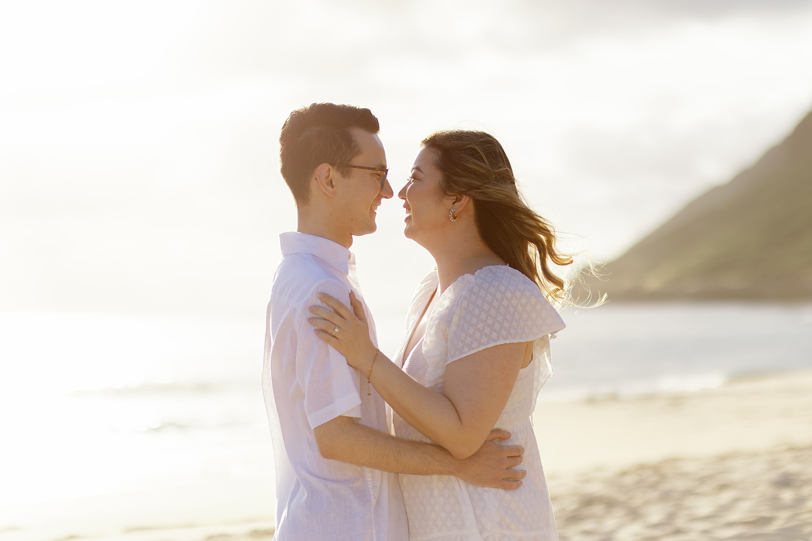 a couple embracing at sunset for their engagement session on the beach